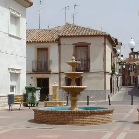 Plaza peatonal con fuente central y farolas
