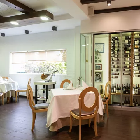 Comedor elegante con vinoteca acristalada y mesas vestidas