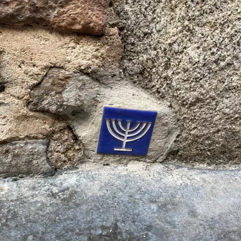 Azulejo con símbolo religioso en muro de piedra