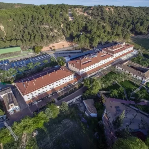 Vista aérea de un complejo turístico con pistas deportivas y zonas ajardinadas.