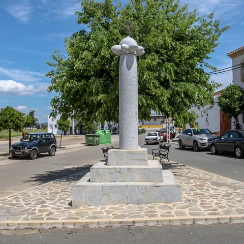 Monumento de piedra en glorieta rodeada de árboles y viviendas