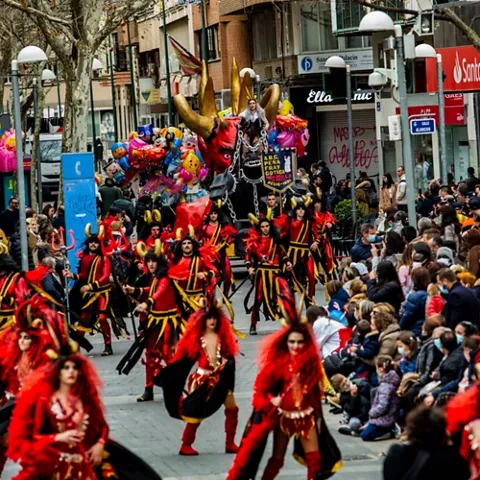 Desfile con personajes disfrazados de figuras fantásticas avanzando entre el público.