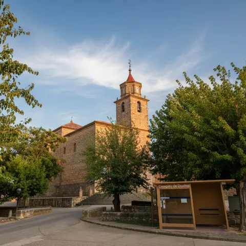 Iglesia de piedra entre árboles junto a espacio urbano