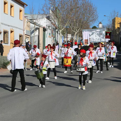 Banda infantil tocando tambores mientras desfila por una calle del pueblo.