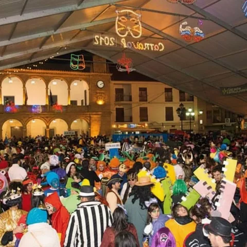 Multitud disfrazada llena plaza cubierta durante fiesta nocturna.