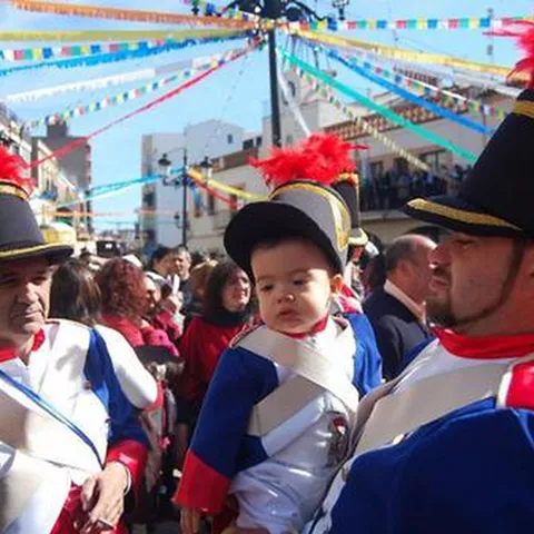 Personas con trajes festivos caminando entre banderines