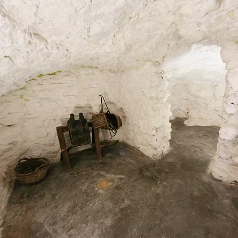 Sala excavada con herramientas tradicionales y suelo de piedra