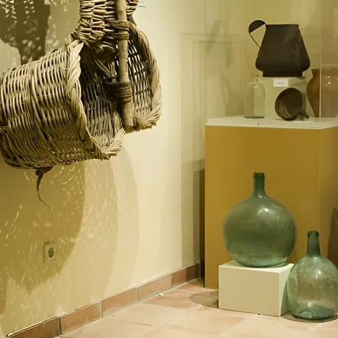 Vitrina con garrafas de vidrio y cestas de mimbre.