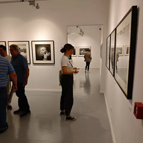 Fachada rosa con balcones y cartel vertical iluminado.