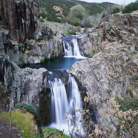 Cascada encajada entre rocas y vegetación.