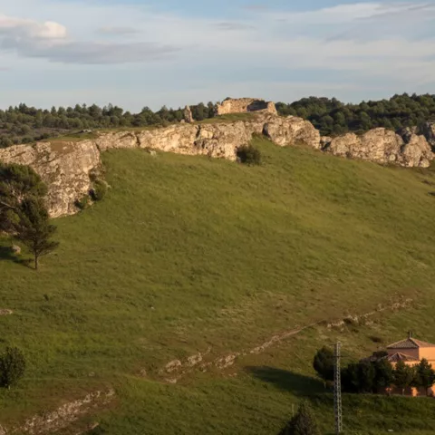 Restos de fortaleza junto a cueva en cresta rocosa.