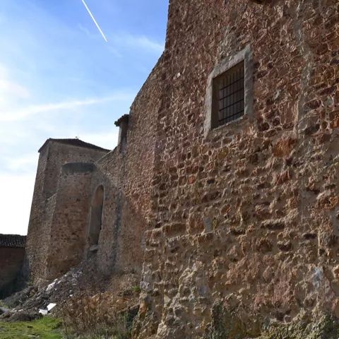 Muro de piedra con ventana enrejada.