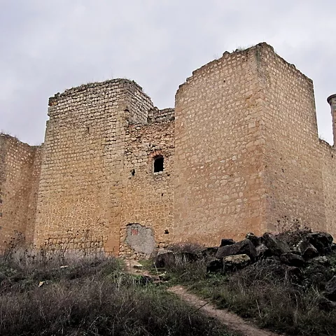 Fortaleza de piedra en paisaje abierto y nublado.