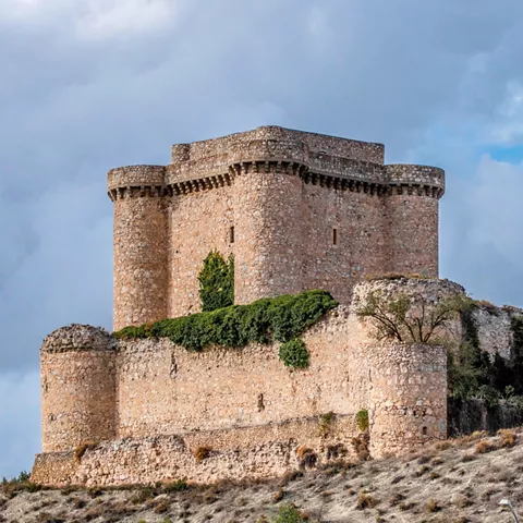 Castillo de piedra con murallas en paisaje rural