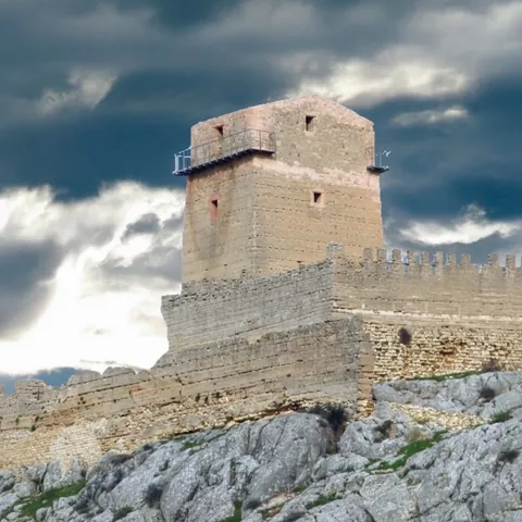 Torre defensiva y murallas de piedra bajo cielo nublado.