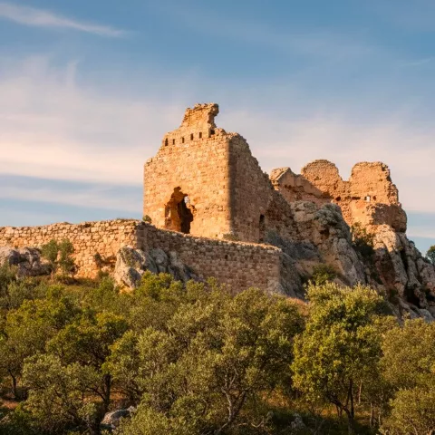 Torre de piedra semiderruida iluminada por luz dorada.