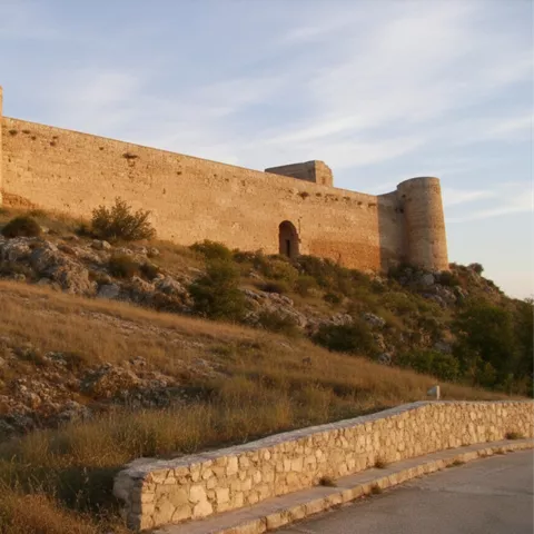 Murallas y torres iluminadas por luz dorada.