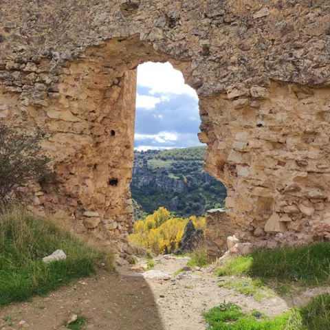Ventana en muro derruido con vistas al valle.