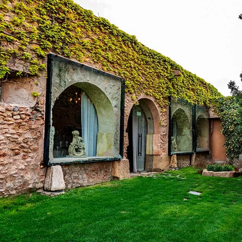 Espacio ajardinado con arcos de piedra y muros cubiertos de vegetación