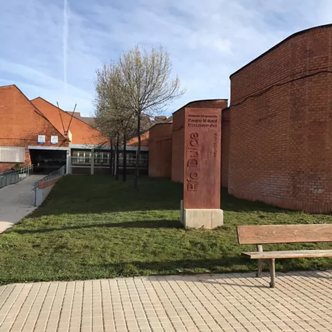 Edificio moderno de ladrillo con zona ajardinada y acceso peatonal.
