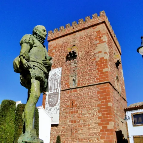 Estatua de Cervantes junto a torre histórica