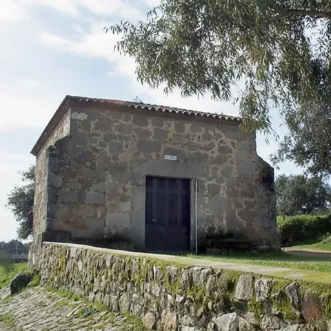 Pequeña ermita de piedra rodeada de vegetación