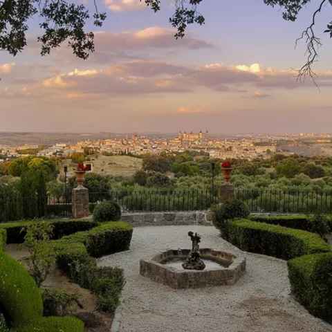 Jardín geométrico con fuente central y vista panorámica al fondo.