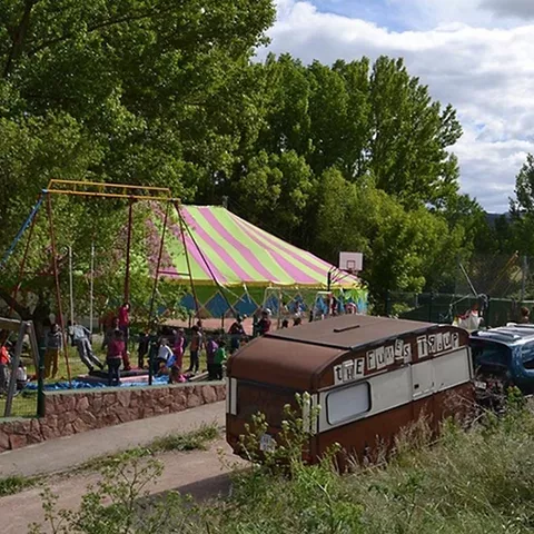 Carpa de circo instalada en un parque con actividades infantiles y juegos