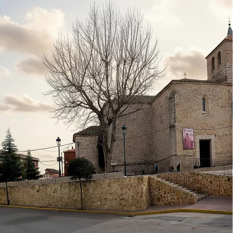 Calle tranquila junto a edificio religioso y muro de piedra