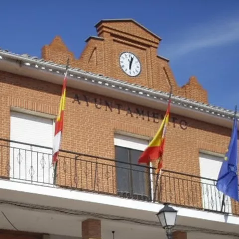 Edificio municipal de ladrillo con banderas en la fachada