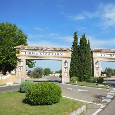 Arco de acceso urbano flanqueado por zonas ajardinadas
