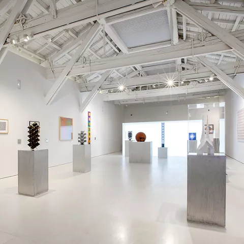 Sala amplia con pedestales y arte abstracto.