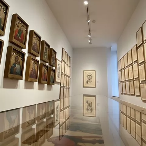 Pasillo con dibujos enmarcados y reflejo en superficie pulida.