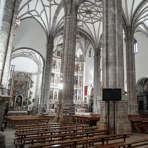 Interior de iglesia con columnas de piedra y bancos de madera