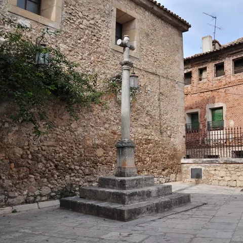 Plaza histórica con cruz de piedra.