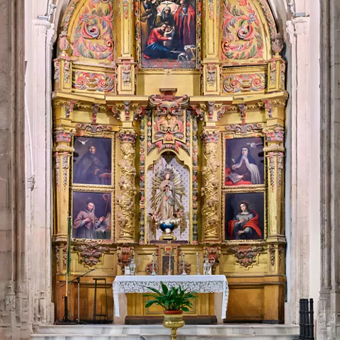 Retablo dorado con pinturas y escultura central sobre el altar