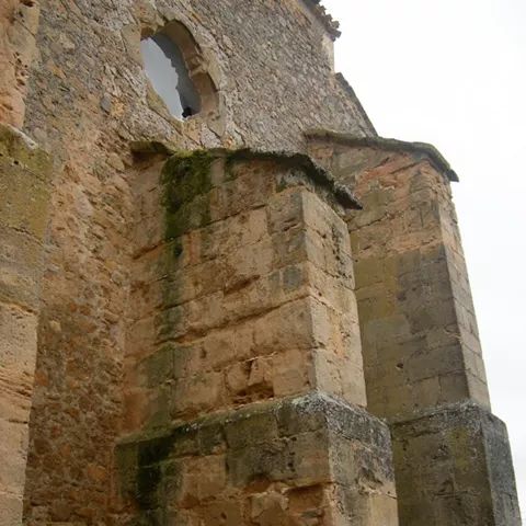 Detalle de contrafuertes de piedra y ventana circular en un muro.