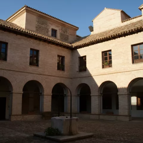 Patio interior con arcos de medio punto y pozo central en edificio histórico.