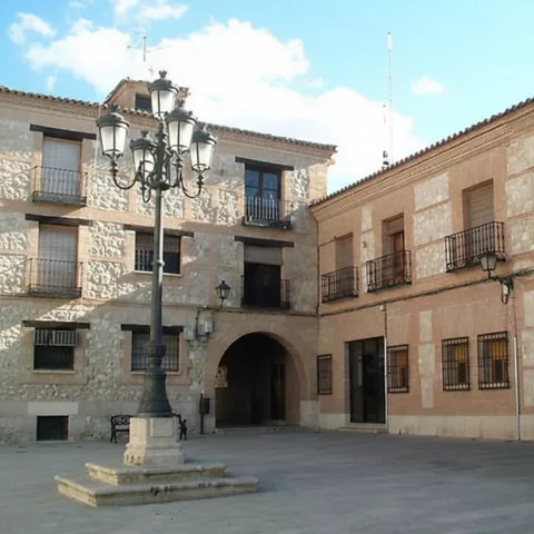 Plaza urbana con edificios de piedra y ladrillo vistos desde un ángulo lateral, entorno tranquilo.