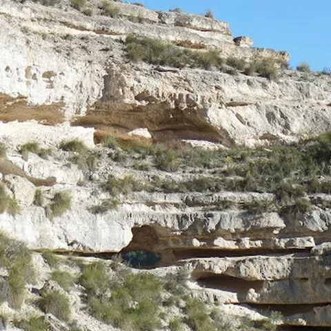 Detalle de estratos rocosos con pequeñas cuevas excavadas en la pared.