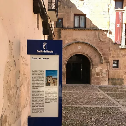 Panel informativo frente a edificio histórico de piedra.