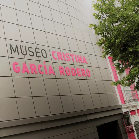 Fachada moderna de museo con rótulo y árboles en primer plano
