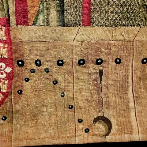 Detalle de tapiz medieval con bordado decorativo y elementos simbólicos
