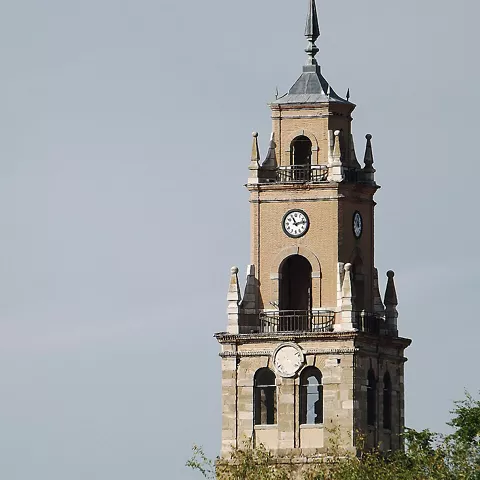 Torre campanario de ladrillo sobre las casas del pueblo.