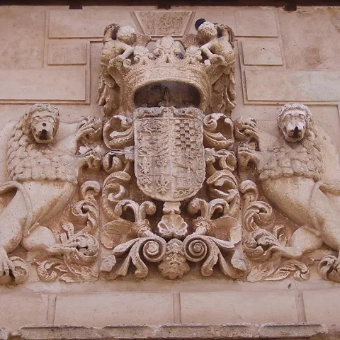 Escudo heráldico tallado en piedra con figuras de leones.