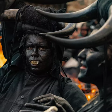 Rostro pintado de negro entre cuernos y fuego.