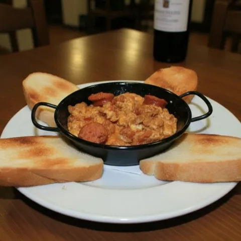 Revuelto tradicional con embutido acompañado de rebanadas de pan tostado