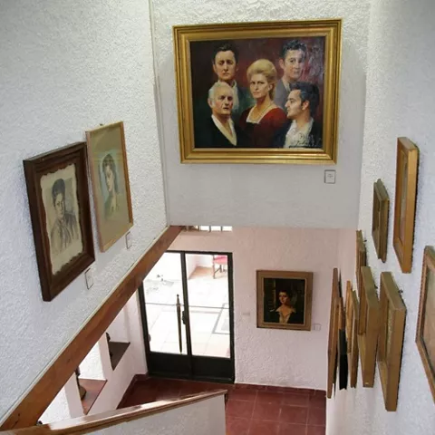 Escalera interior con paredes blancas y retratos colgados