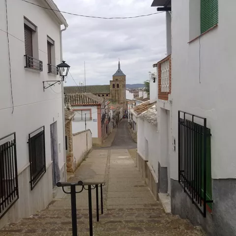 Calle con escaleras y torre de iglesia al fondo