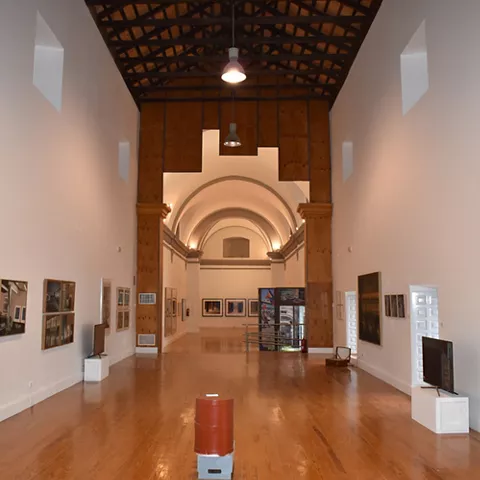 Sala expositiva amplia con suelo de madera y obras contemporáneas